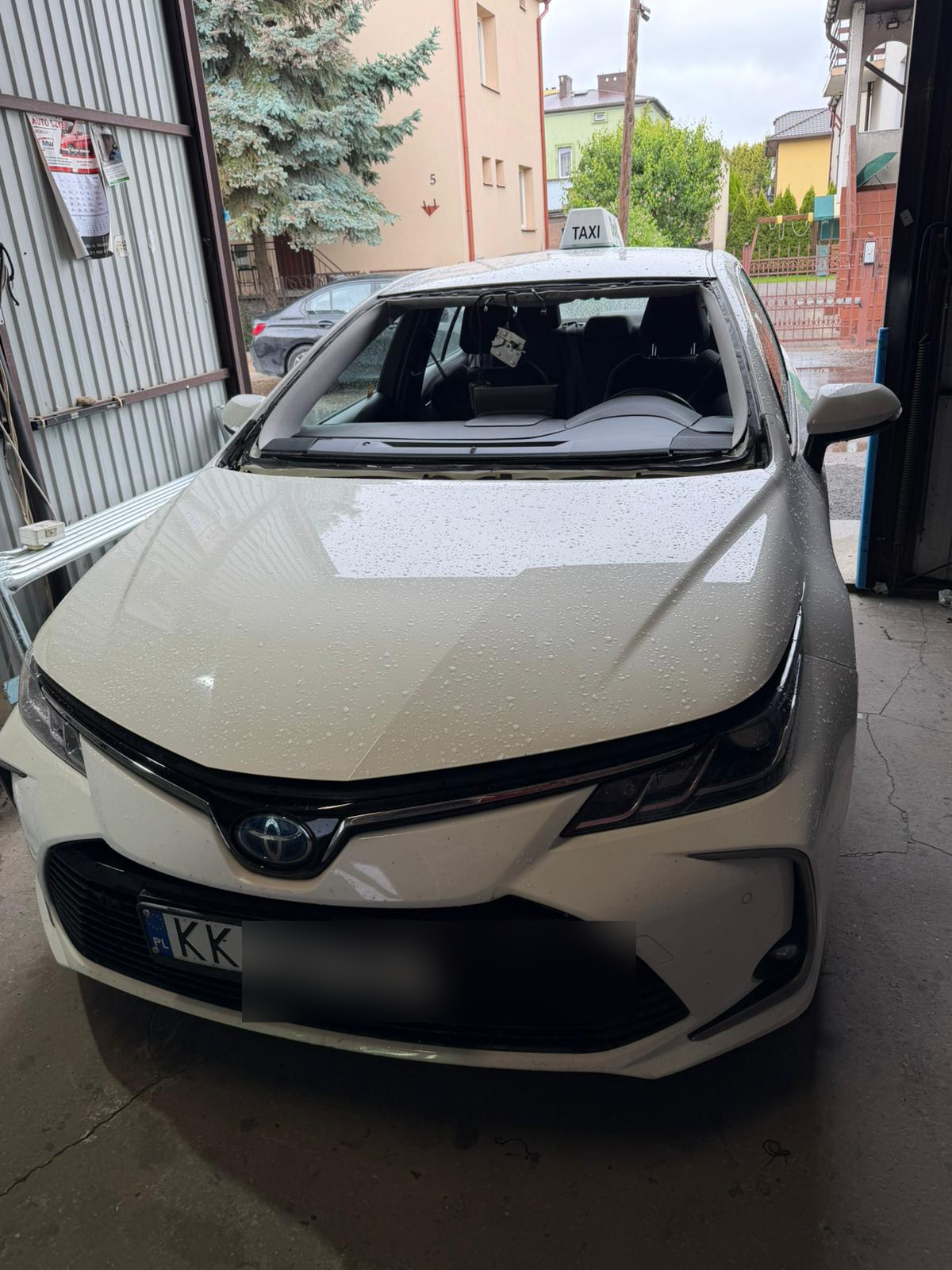 Toyota taxi z uszkodzoną przednią szybą przed wymianą w warsztacie